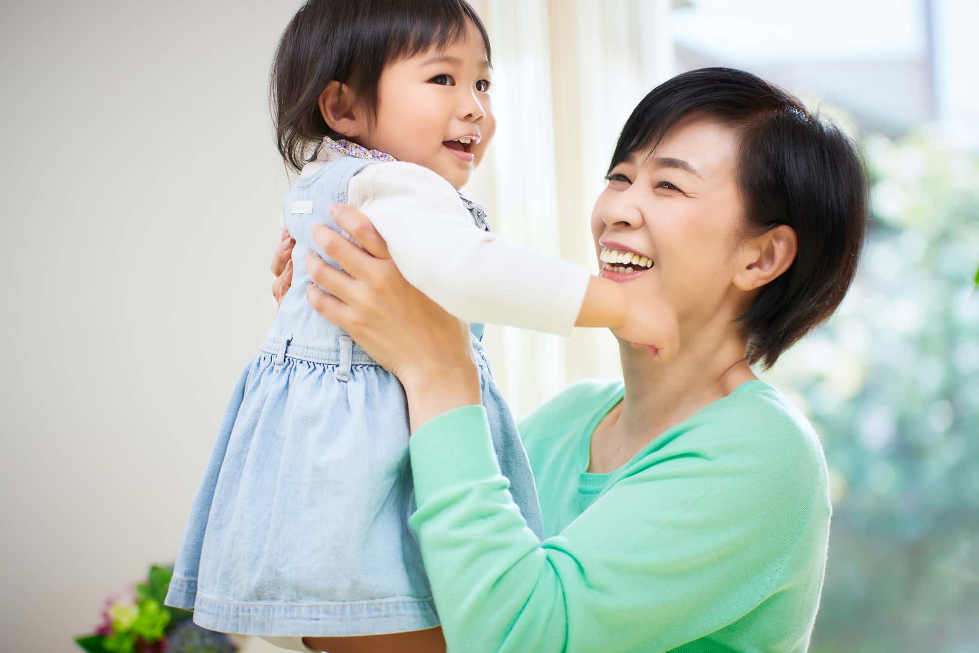 自分に合った入れ歯をして笑顔の女性が孫と遊んでいる