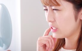 口内炎が痛くて鏡で確認しようとしている女性