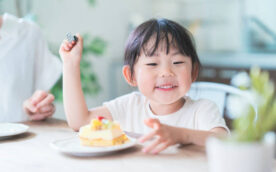 Asian mom and daughter eating cake at dining table at home