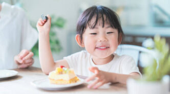 Asian mom and daughter eating cake at dining table at home