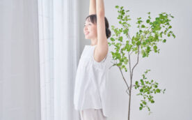 A woman taking a deep breath by a bright window