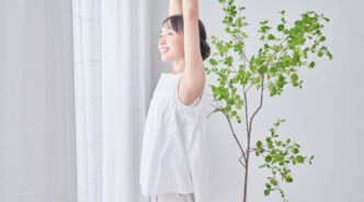 A woman taking a deep breath by a bright window