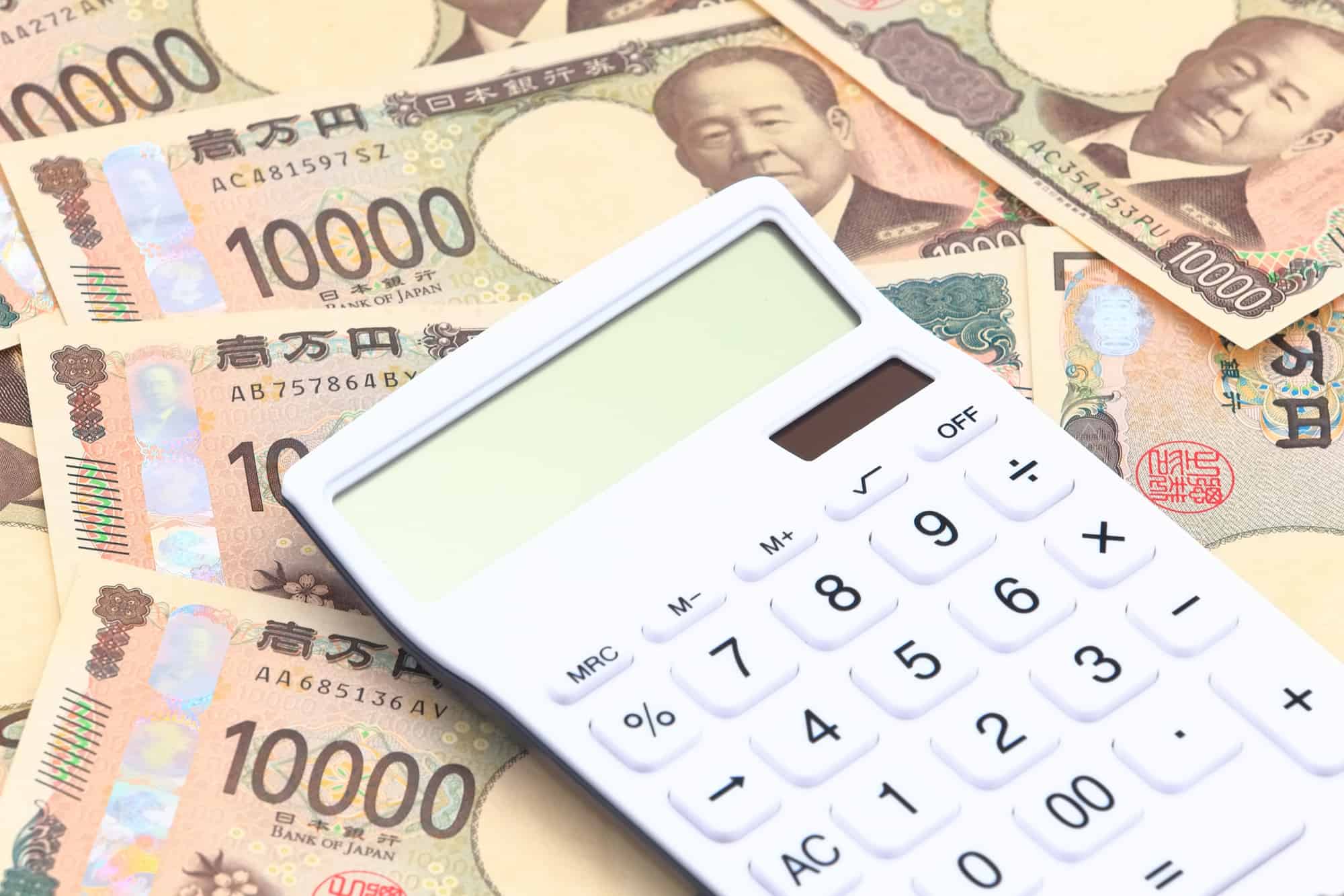 インプラントが高額であることを示す計算機とたくさんの一万円札