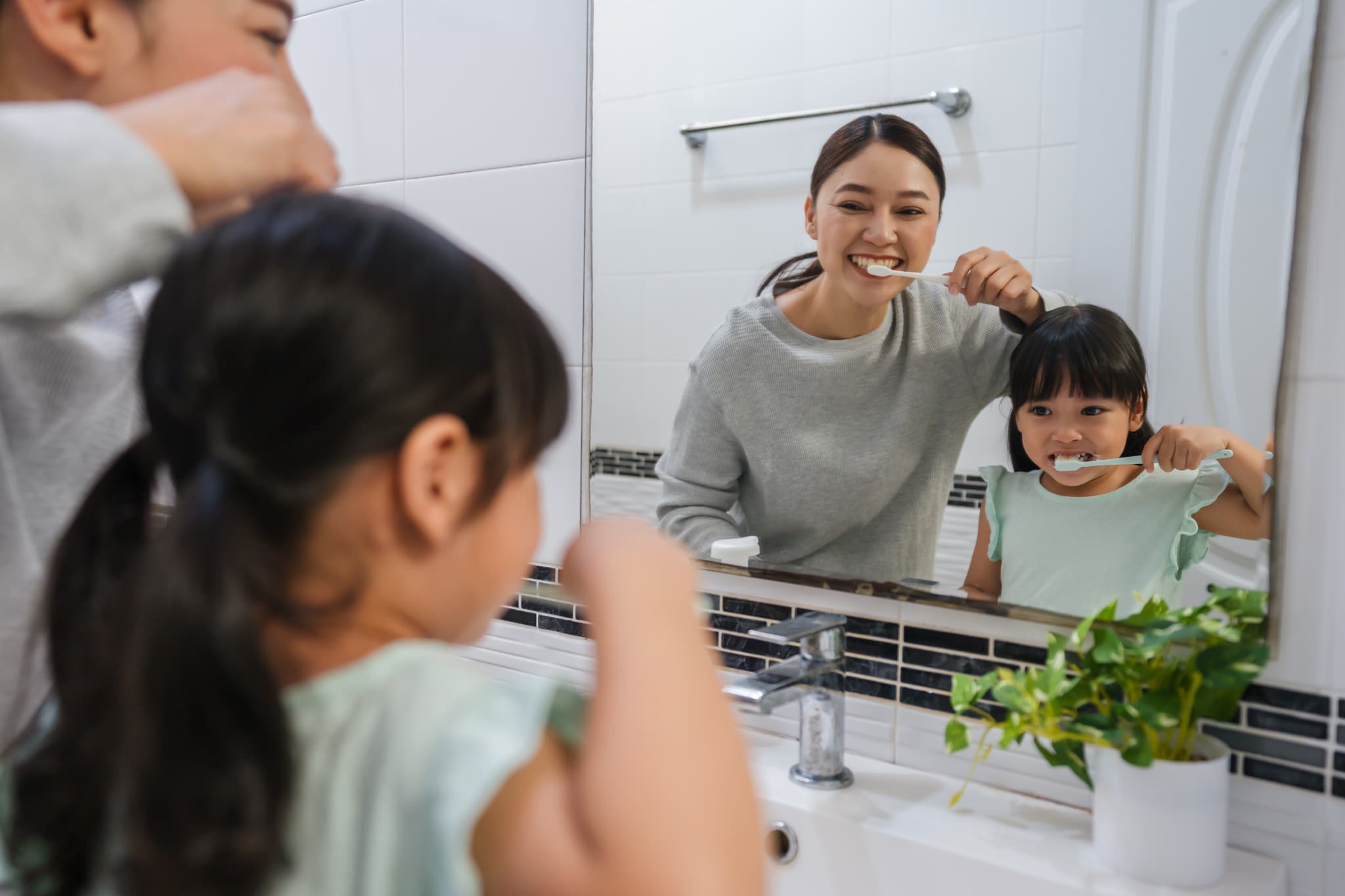 鏡を見ながら歯を磨くことを子どもに教える母親